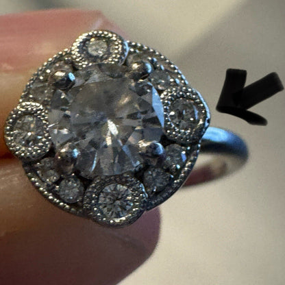 Close-up of an 18K white gold diamond halo ring showing filigree detail and band profile