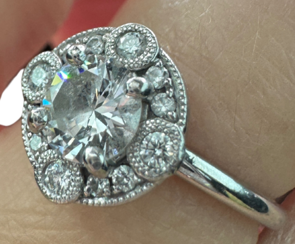 Close-up of Laurence Bruyninckx 18K white gold diamond halo ring shown on finger, featuring round center diamond and pavé halo