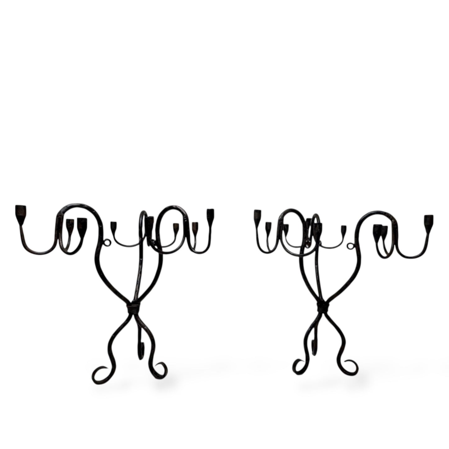 Pair of vintage hand-wrought iron candelabra with curved arms and sculptural bases, photographed on a white background.