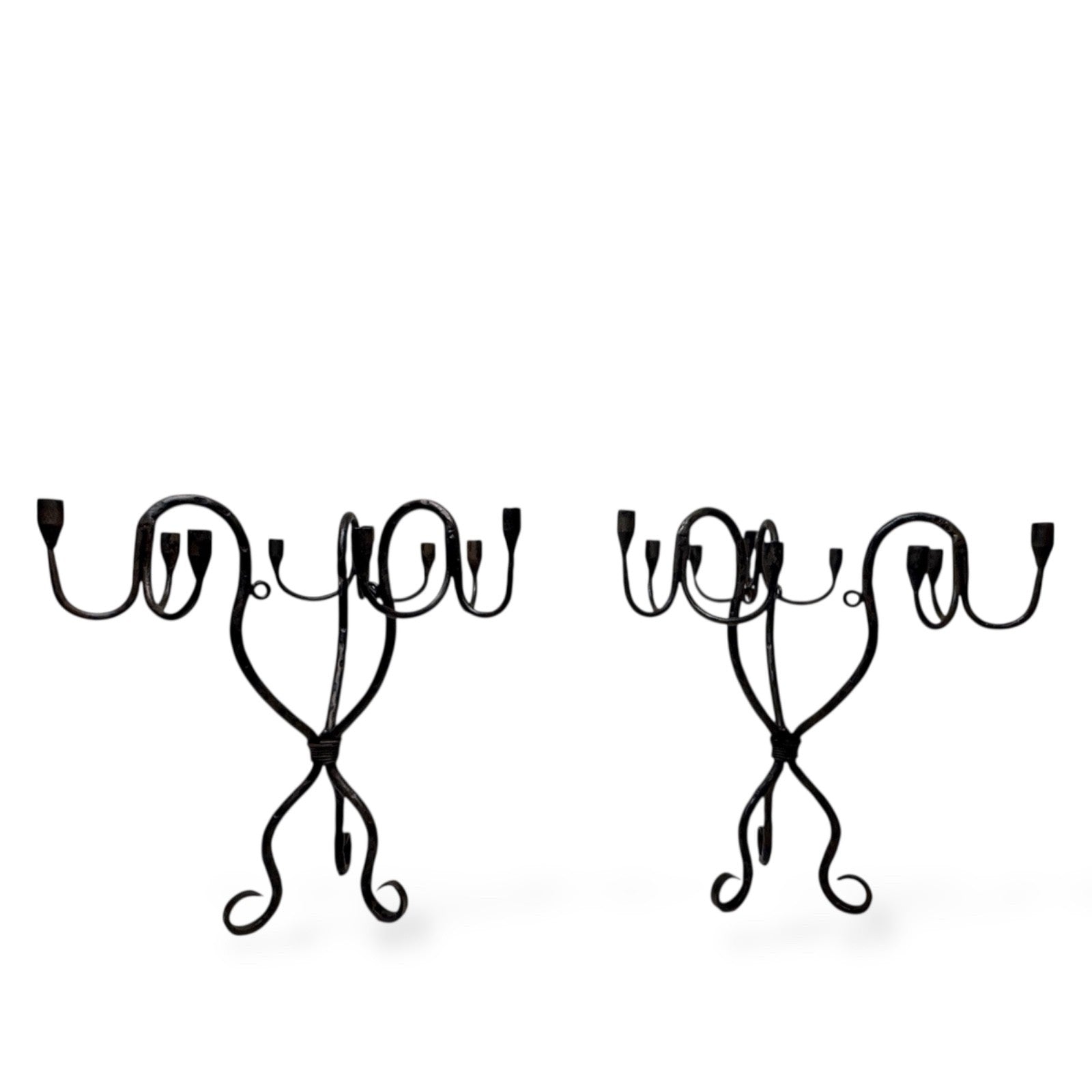 Pair of vintage hand-wrought iron candelabra with curved arms and sculptural bases, photographed on a white background.