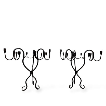 Pair of vintage hand-wrought iron candelabra with curved arms and sculptural bases, photographed on a white background.