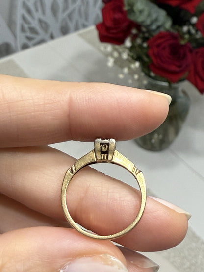 Vintage 14K gold diamond illusion head ring held between fingers, showing band and setting details with decorative background