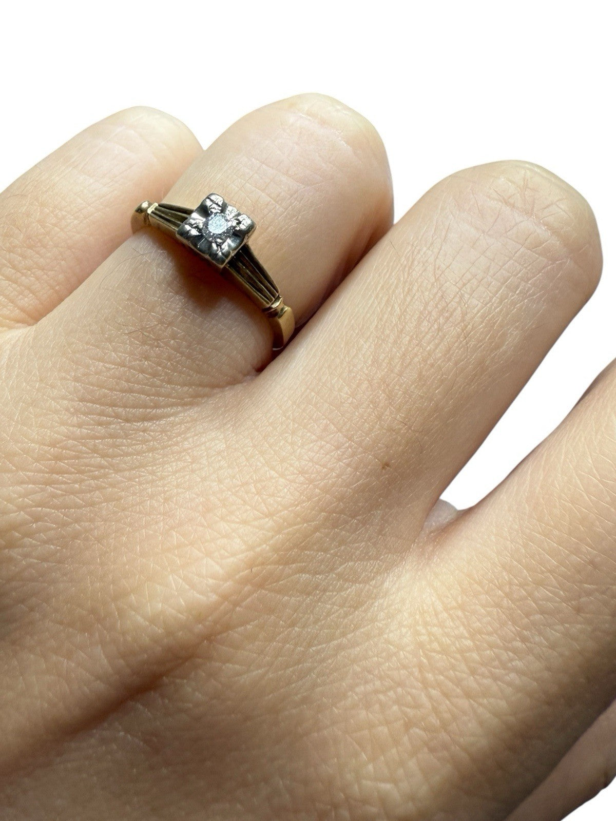Close-up of vintage 14K gold diamond illusion head ring on a finger