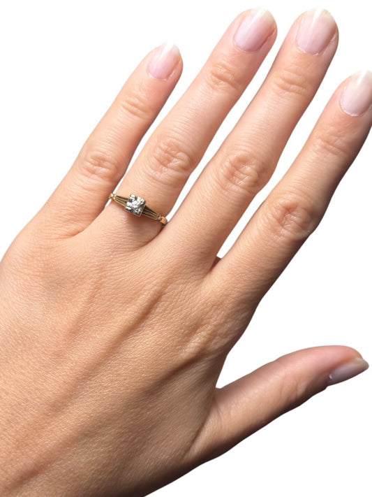 Hand wearing a vintage mid-century 14K gold diamond illusion head ring with white gold accent on a white background